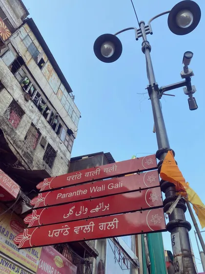 The iconic sign for 'Paranthe Wali Gali' in Chandni Chowk. While famous, we offer an honest take on which spots are truly worth your time, guiding you to hidden gems beyond the main tourist trail.