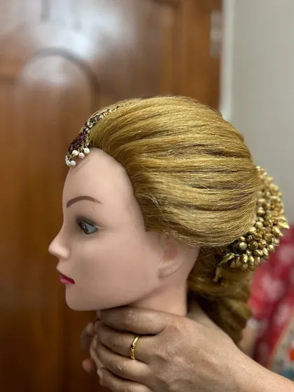 A side profile view of a completed practice look, showing how the front hairstyle, maang tika, and bun accessory all work together harmoniously.