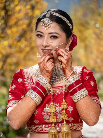 A joyful portrait of the bride in her red lehenga, set against the beautiful autumn colors of Sangla Valley.