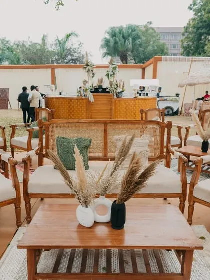 A rustic-chic lounge area for a 'Farmer's Market' themed event, with wooden furniture, cane details, and pampas grass decor.