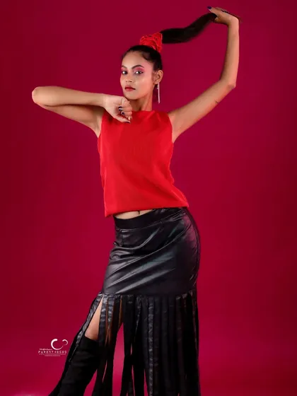 A strong and confident pose that highlights the textures of the outfit, from the knit top to the leather fringe.