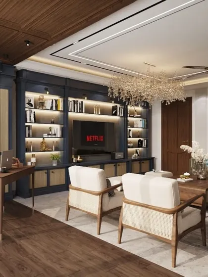 A multifunctional living space designed for a modern family. This room combines a cozy TV lounge with a dedicated work-from-home nook, all unified by classic blue cabinetry, warm wood flooring, and elegant, comfortable furniture.