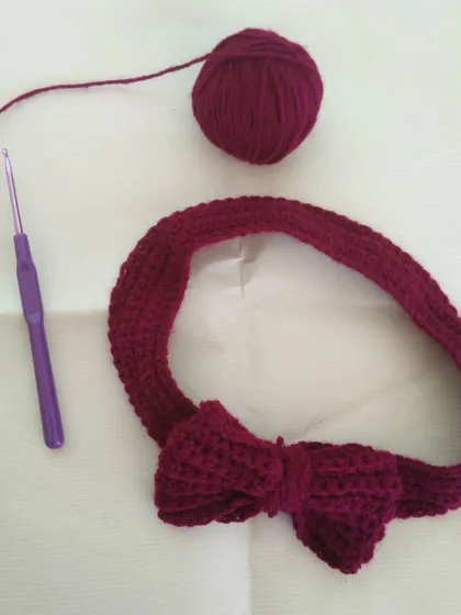 Here you can see my process for creating a bow headband. Each one is crocheted by hand with soft yarn, like this piece in a deep maroon color.