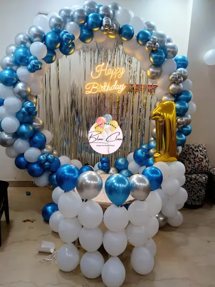 A full balloon ring in blue, white, and silver with a shimmer curtain for a first birthday.