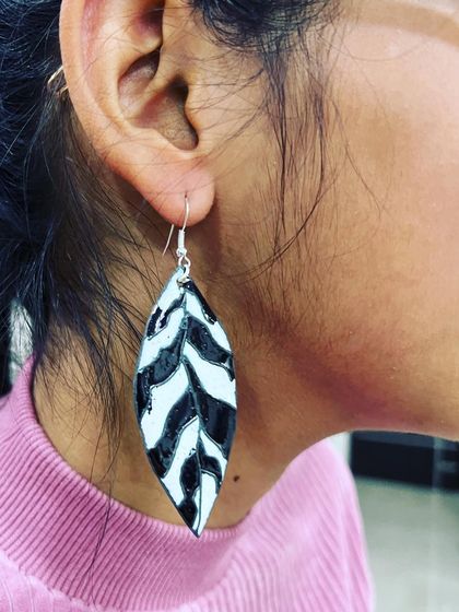 A student wearing the beautiful leaf-patterned enamel earrings she created from scratch in our two-day workshop.