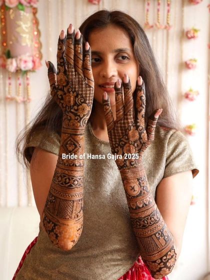 A bride with elegant, full-arm mehendi on the back of her hands. The design features personalized initials and traditional bands, creating a look that is both timeless and personal.