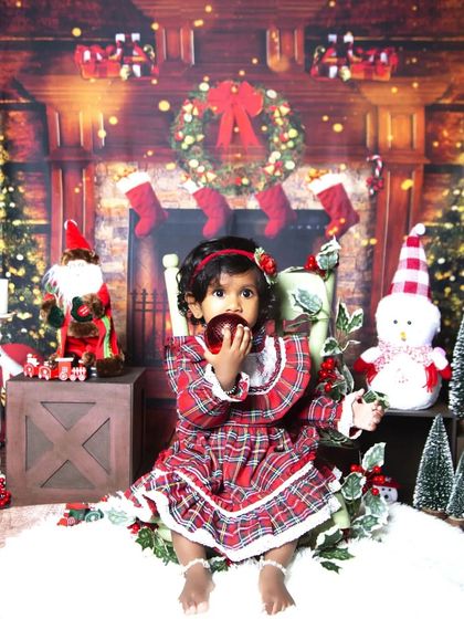 A candid moment from the Christmas session, as the toddler curiously inspects a shiny red ornament.