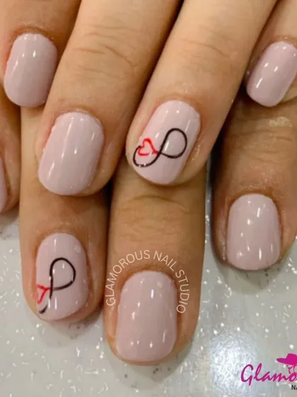 Simple and sweet, this manicure features a soft, natural pink base with a delicate, hand-painted infinity symbol intertwined with a heart.