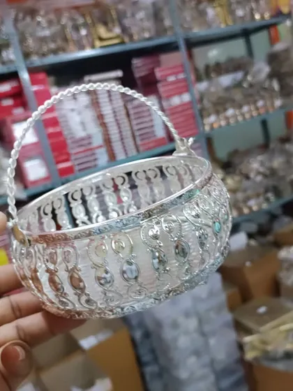 A hand-held view of a German silver flower basket, showing its intricate latticework and sturdy handle.