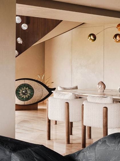 A glimpse of the dining area from the living room, with the eye-shaped sculpture in the background. This composition highlights the open, flowing nature of the space and its art-filled corners.