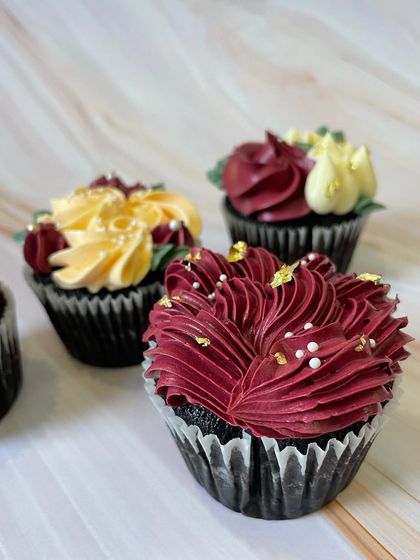 This image highlights the variety in my floral cupcake designs. You can see different piping techniques used to create distinct flower shapes, all tied together with a cohesive color palette and elegant gold flake accents.