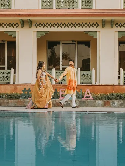 A serene moment during the Haldi festivities, as the couple takes a stroll by the pool. The reflection in the water adds a beautiful, artistic touch to the photograph.