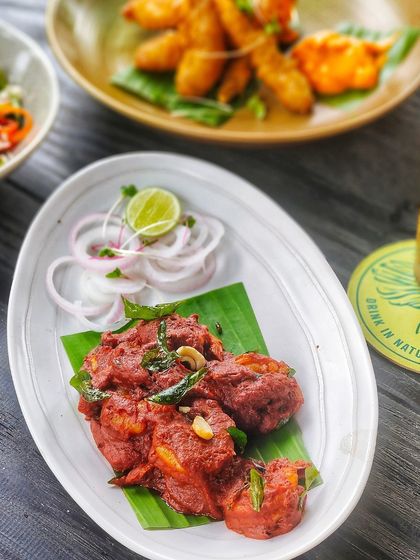 A plate of spicy chicken 65, a popular South Indian appetizer, served on a banana leaf.