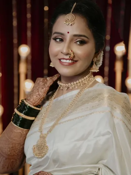 A radiant bridal portrait. The bride's happy smile and the warm, glowing lights in the background create a photograph that is full of joy and celebration.