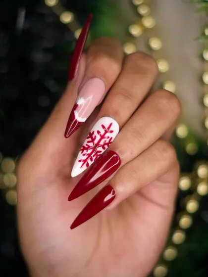This angle showcases the sharp, clean lines of the stiletto extensions and the placement of the snowflake and Santa hat art. The combination of red, white, and nude creates a balanced holiday look.