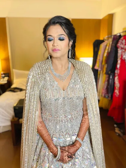 A close-up of the shimmery eye makeup. The cool tones of the eyeshadow perfectly complement the silver sequins of her cape gown.