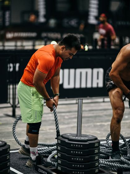 Setting up for the sled pull at Hyrox Mumbai. Notice the stacked weights and the long rope. Preparation for this station involves building a powerful posterior chain and immense grip strength.