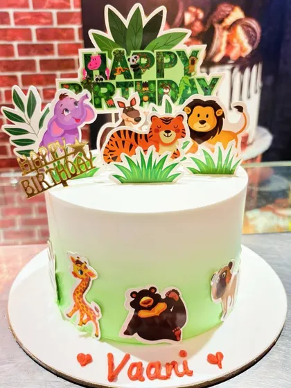 A simple and cute jungle-themed cake with cartoon animal toppers.