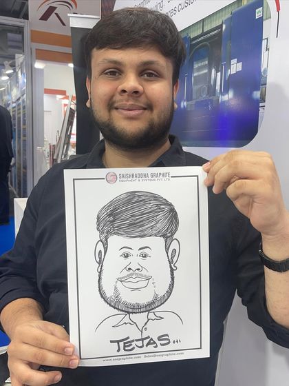 A guest from an exhibition at the NESCO center in Mumbai, holding his caricature drawn on paper branded by Saikrishna Graphite.