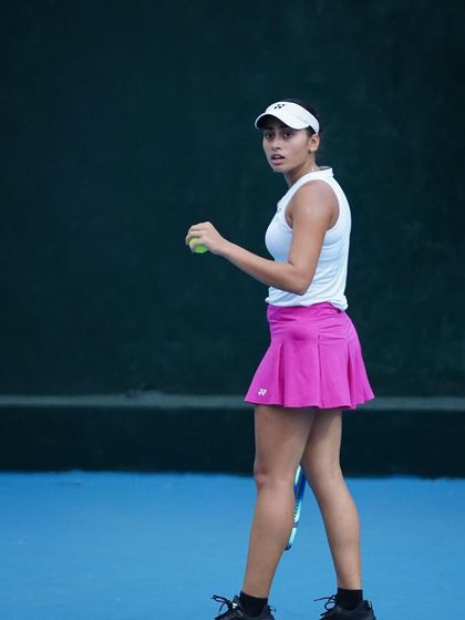 A player holds her ready position on the baseline, eyes fixed on the opponent, showcasing the mental and physical preparedness we train.