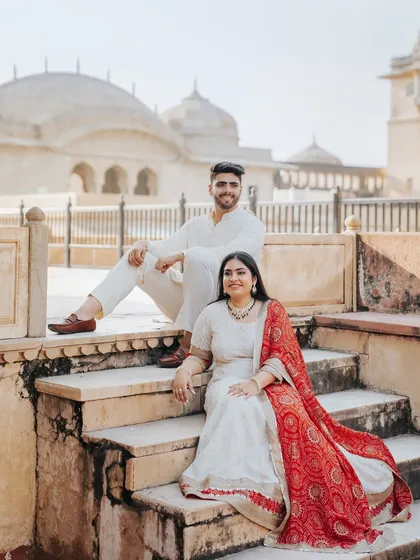 A regal and relaxed portrait of the couple seated on the steps of Amer Fort, looking like modern-day royalty.