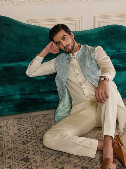 The cool tones of the blue jacket against the warm green velvet couch create a visually appealing contrast. This outfit is designed for both comfort and style.