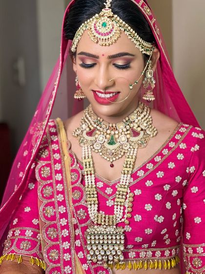 This bride looks absolutely radiant in a heavy polki and pearl layered set, complete with a matha patti and nath, perfectly complementing her bright pink lehenga.