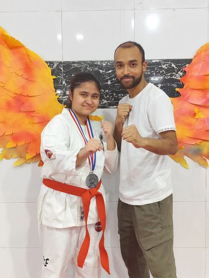 A student with her coach, celebrating a silver medal win. The wings in the background are fitting for our high-flying athletes.