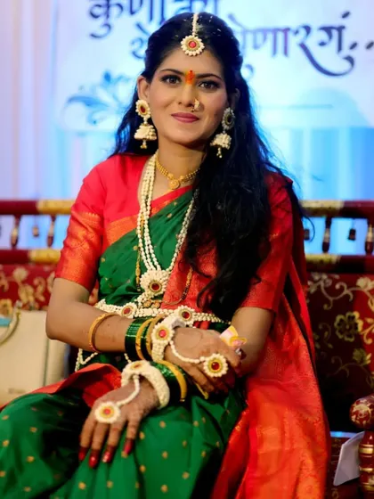 A traditional dohale jevan look. The client is seated on a decorated swing, wearing our classic white and orange floral jewellery set.
