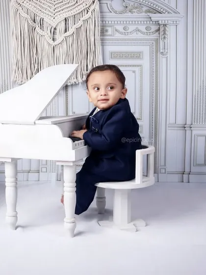 A thoughtful moment at the piano. This image captures the quiet curiosity of a child exploring a new instrument in a beautiful, classic setting.