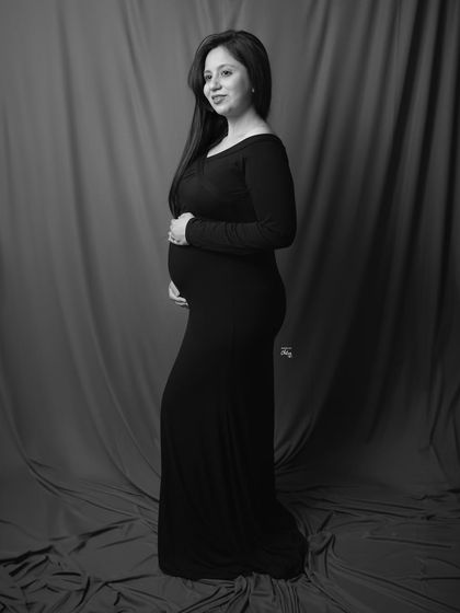 A simple and elegant solo portrait in black and white. The classic pose against a simple backdrop puts all the focus on the mother-to-be.