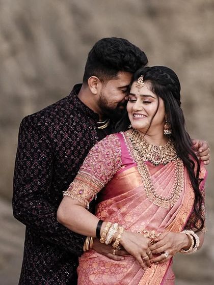A romantic portrait of a couple against a natural rock background. The groom's embrace and the bride's happy smile make this a lovely, intimate shot.