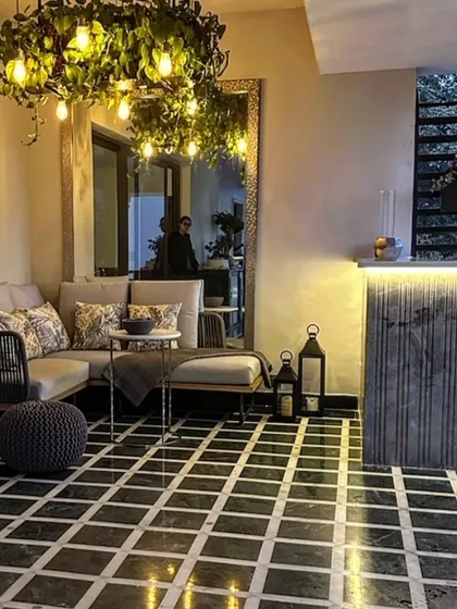 This image shows another angle of the cozy balcony living space, highlighting how the indoor and outdoor areas flow together. The plant chandelier serves as a beautiful bridge between the two, visible from inside the home.