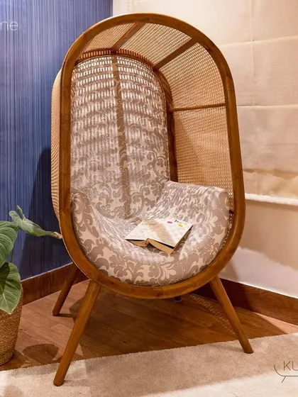 The 'Dome' chair styled in a cozy corner. Its unique shape and natural materials create an inviting nook for reading or quiet contemplation.
