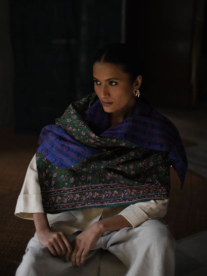 A quiet, contemplative moment captured for Wandering Silk. The model is wrapped in a beautiful handwoven shawl, and the soft, directional light highlights the rich colors and patterns of the textile.