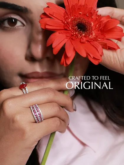 Crafted to feel original. This image captures the feeling of wearing pieces that are uniquely yours, featuring a heart-shaped ruby ring and a wide ruby and diamond eternity band. The handpicked gemstones and handcrafted settings define this personal luxury.