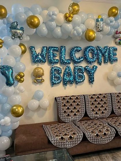 This is a popular and budget-friendly option for a living room setup. It features a "Welcome Baby" foil balloon arrangement on the wall, framed by a blue and white organic balloon garland with gold accents.