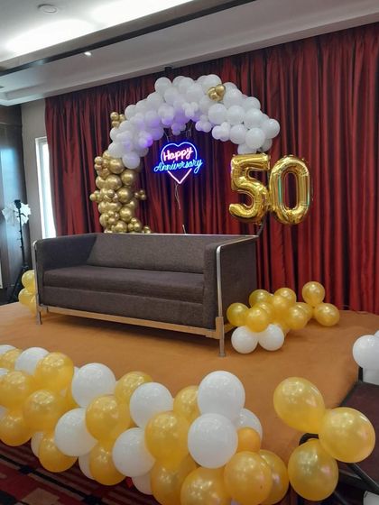 The lighting plays a key role in this 50th anniversary setup. The blue neon sign adds a modern touch to the classic gold and white color scheme.