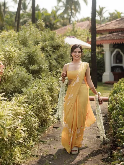 The bride walking through a lush green path at her Goa wedding venue, looking serene and happy.