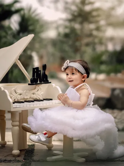A little angel at the piano. Dressed in a fluffy white dress, she looks absolutely ethereal while playing her tune in a lovely garden setting.