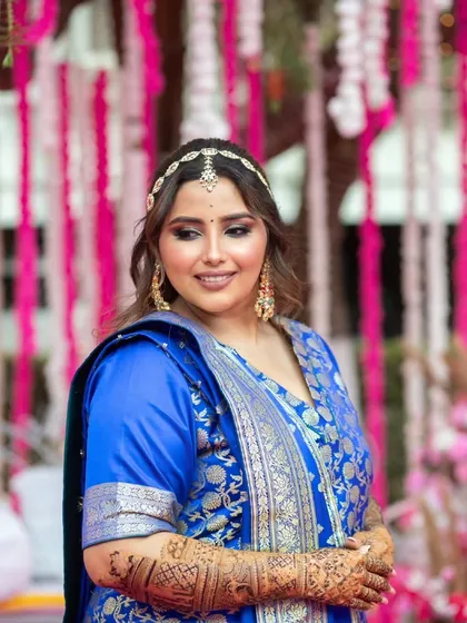 A vibrant Mehendi look for a wedding guest. The royal blue outfit is paired with a soft smokey eye and loose, wavy hair.