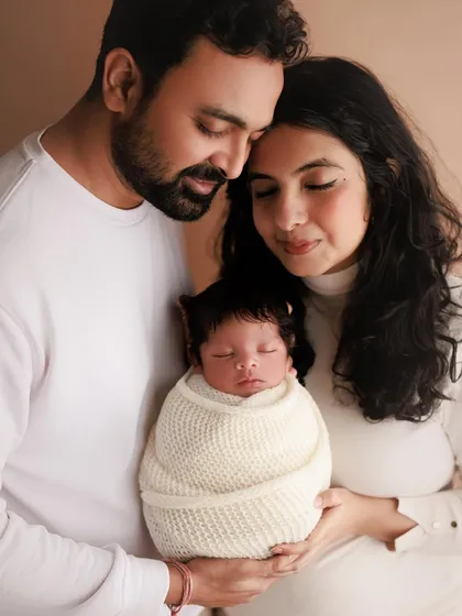 A simple, beautiful portrait of a new family of three. The coordinated white outfits and the parents' loving expressions make this a timeless keepsake.