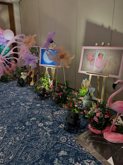 A walkway decorated with lush flower arrangements and framed photos of the birthday girl, creating a personal and enchanting path for guests.