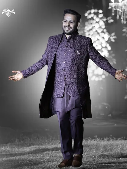 A moment of pure joy. This groom celebrates in our custom three-piece ensemble in a deep aubergine, featuring a textured jacket and waistcoat for a layered, regal look.