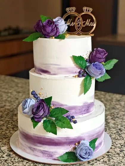 A classic three-tier wedding cake in a beautiful lavender watercolor effect, finished with delicate sugar flowers. I used whipped cream for a light, delicious taste, proving that large, structured cakes can be both stunning and free of heavy fondant.