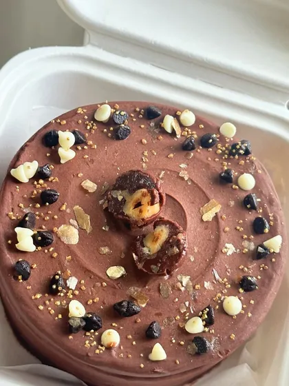 A decadent chocolate bento cake topped with Ferrero Rocher, chocolate chips, and gold sprinkles. A dream come true for any chocolate lover.