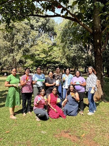 A happy group of women poses with their finished artworks after an outdoor painting session in a park. These art picnics are a wonderful way to connect with nature, creativity, and like-minded people.