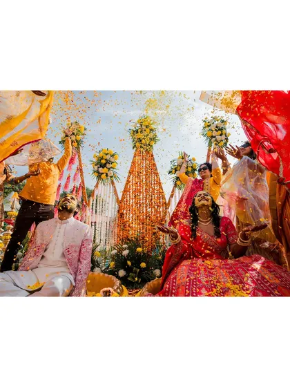 The vibrant energy of a Haldi ceremony is infectious. This shot captures the couple surrounded by friends, immersed in a storm of flower petals and laughter, a perfect kick-off to the wedding festivities.