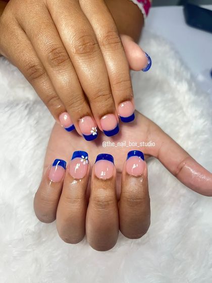 A modern take on the French manicure. I used a bold royal blue for the tips on these extensions and added a small, delicate hand-painted white flower for a unique touch.