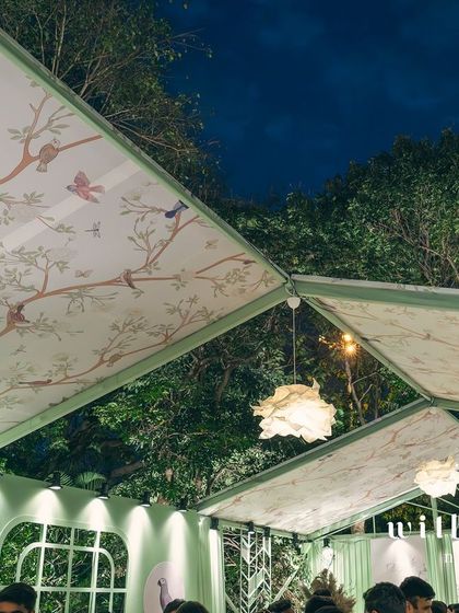 The custom-printed ceiling of 'The Conservatory' tent, featuring a beautiful bird and branch motif that glows under the evening sky.